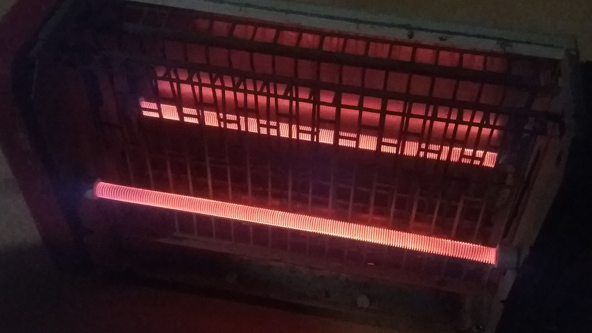 Photographie de l'intérieur d'un grille-pain. La résistance brille d'une couleur rouge orangé.